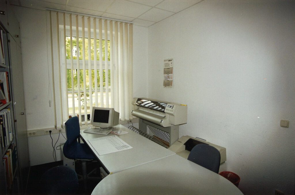 Büro mit Plotter, Röhrenmonitor und Schreibtisch für die Planung